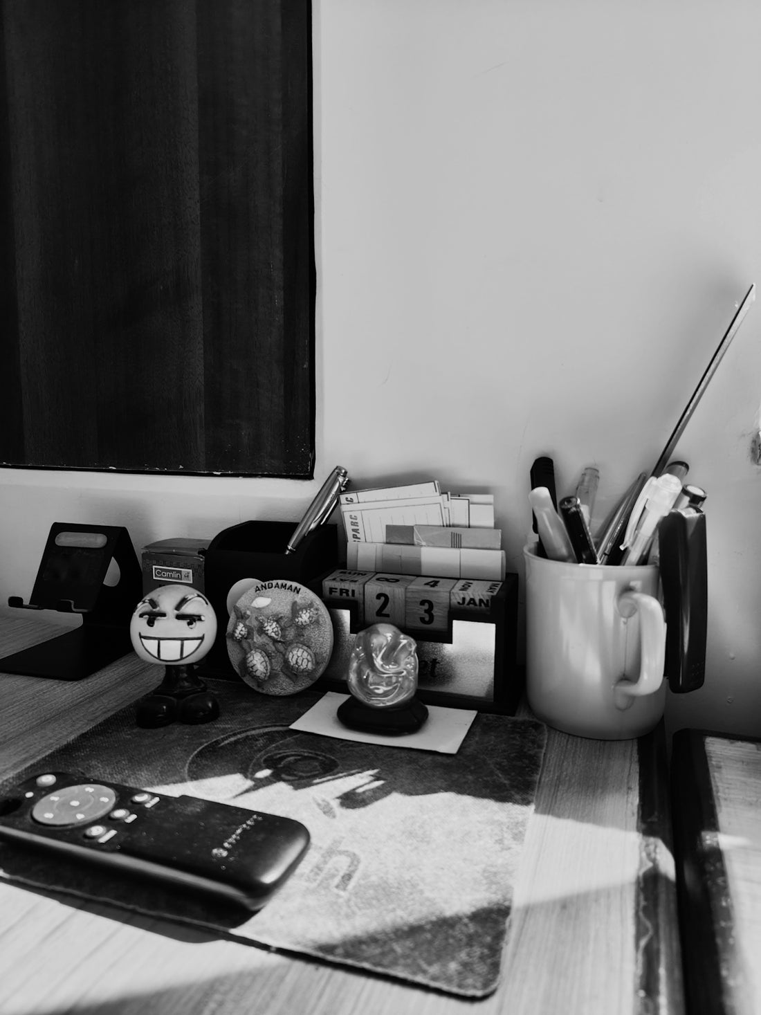 Black and white cluttered desk with remote and stationery